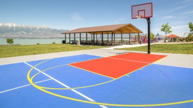 arka planda bir piknik pavyonu ve oyun alanı ile çerçeve Açık basketbol sahası