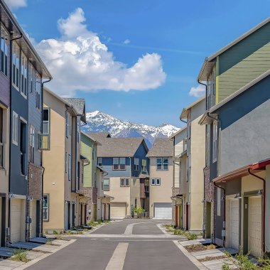 Kar kaplı dağ ve bulutlu gökyüzü manzaralı evlerin ortasında Square Road