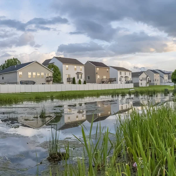 Plaza Hermosas casas de varios pisos construidas frente a un estanque cubierto de hierba y brillante — Foto de Stock