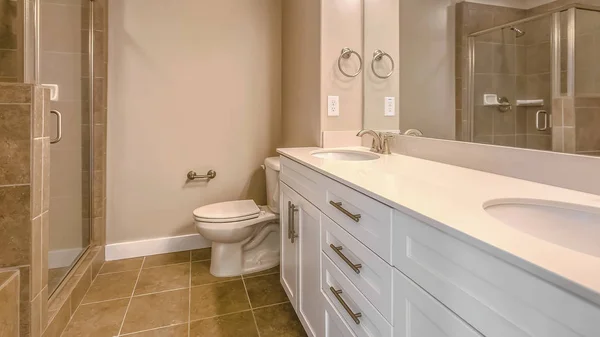 Panorama frame Vaidade com pia dupla adjacente ao banheiro dentro de um banheiro bem iluminado — Fotografia de Stock