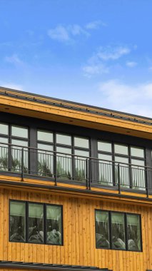 Mavi gökyüzü ve beyaz bulutlar altında dikey ahşap tahta duvar ile Dikey Ev dış