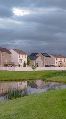 Balkonlu ve metrelik evlerin önünde köprülü dikey park yolu ve gölet