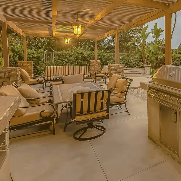 frame Outdoor kitchen and dining area under a pergola at the spacious patio of a home