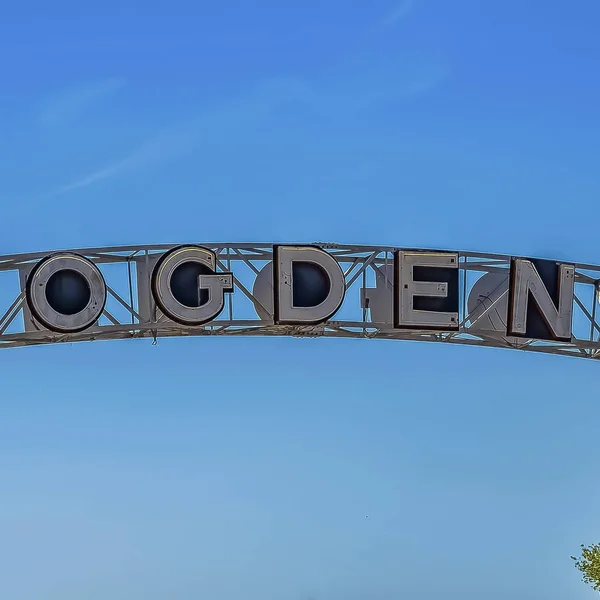 frame Welcome arch at the city of Ogden in Utah against lush treetops and blue sky