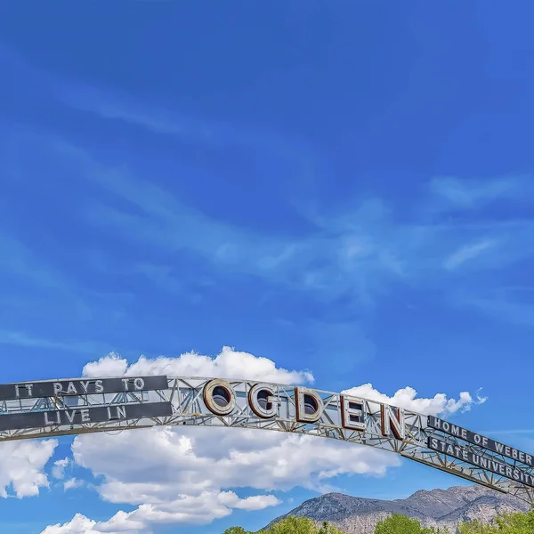 Square frame Welcome arch at the city of Ogden Utah against vivid blue sky and puffy clouds