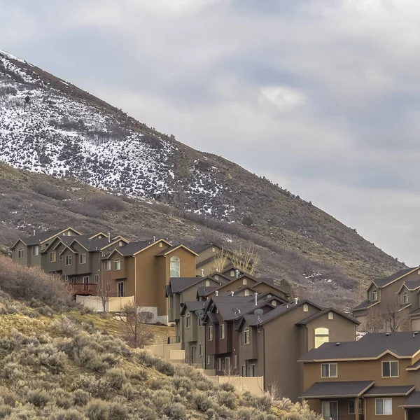 Square Rows of houses built on a mountain slope with view of cloudy sky overhead