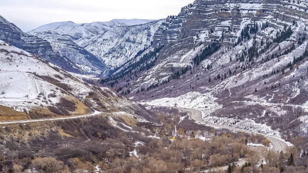 Panorama Camino curvo en medio de una montaña imponente con pendientes cubiertas de nieve fresca — Foto de Stock