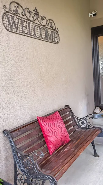 Vertical frame Rustic metal and wood bench with red pillow on the porch of a home