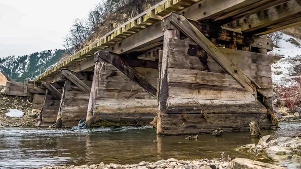 Rustikale Holzbrücke über einen felsigen Bach mit glänzendem Wasser — Stockfoto