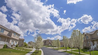 Panorama çerçeve Güneşli bir günde bulutlu mavi gökyüzü altında bir mahallede Döşeli yol ve evler