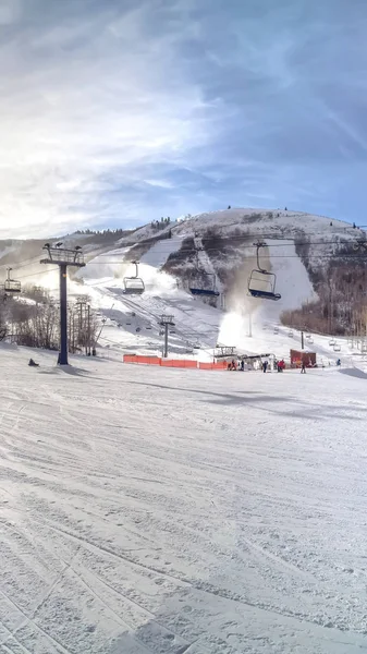 Вертикальный горнолыжный курорт с лыжными подъемниками под облачным голубым небом в солнечный зимний день — стоковое фото