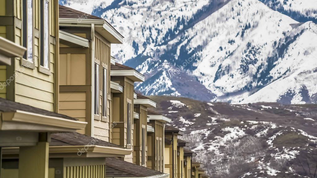 Panorama frame Close up of upper storey of homes against snow blanketed mountain in winter