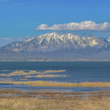Kare çerçeve Mavi gökyüzünü yansıtan vadi ve göl üzerinde yükselen Karlı dağ