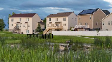 Panorama çerçeve Çok katlı evlerin önünde bir alanın ortasında köprü ile Grassy gölet