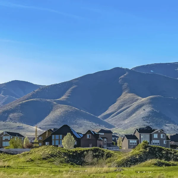 Τετραγωνικά σπίτια σε ένα έδαφος καλυμμένο με χόρτα κάτω από τον γαλάζιο ουρανό σε μια ηλιόλουστη μέρα — Φωτογραφία Αρχείου