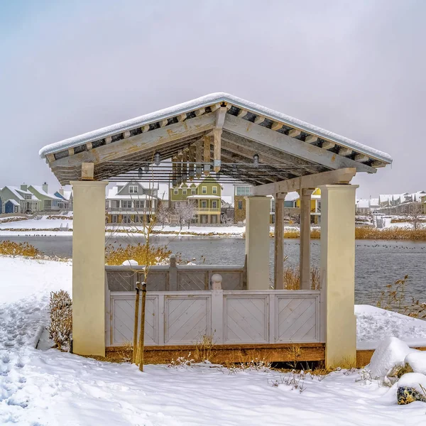 Pavilhão de moldura quadrada na costa coberta de neve de um lago visto em um dia nublado de inverno — Fotografia de Stock