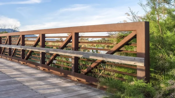 湖の上に木製のデッキと金属ガードレールを持つ橋のフレーム晴れた日の眺め — ストック写真