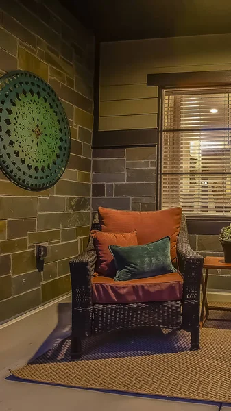 Vertical Wicker chairs and table at the cozy porch of a home viewed at night