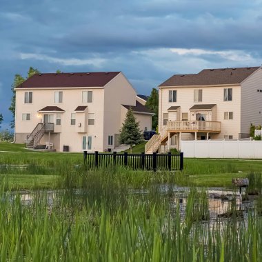 Kare çerçeve Çok katlı evlerin önünde bir alanın ortasında köprü ile Grassy gölet