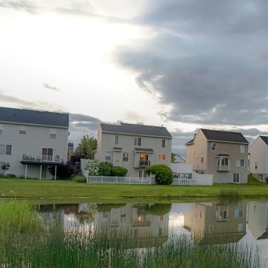 Kare çerçeve Aile evleri ve parlak bulutlu gökyüzü parlak mahalle gölet yansıyan