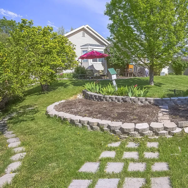 Plaza de jardín césped patio de casa con exuberantes árboles y piedras decorativas de hormigón — Foto de Stock