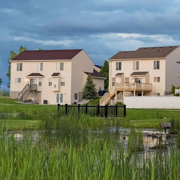 Kare çerçeve Çok katlı evlerin önünde bir alanın ortasında köprü ile Grassy gölet