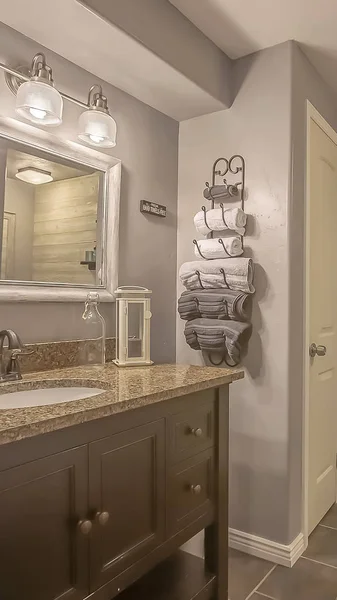 Vertical Mirror and lamps above the vanity inside a bathroom with towel rack and shelves — Stock Photo, Image