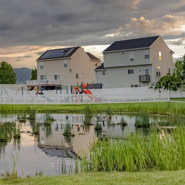 Kare çerçeve Parlak gölet oyun alanı ve çok katlı evler geniş çimenli arazi ile çevrili