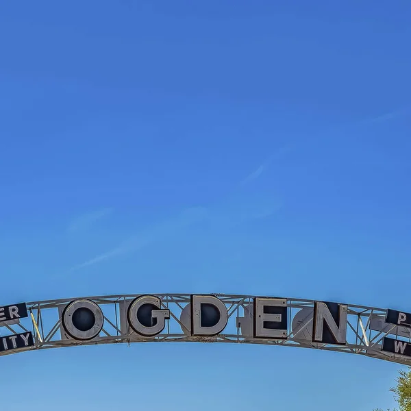 Приветственная арка в городе Огден в штате Юта против пышных деревьев и голубого неба — стоковое фото