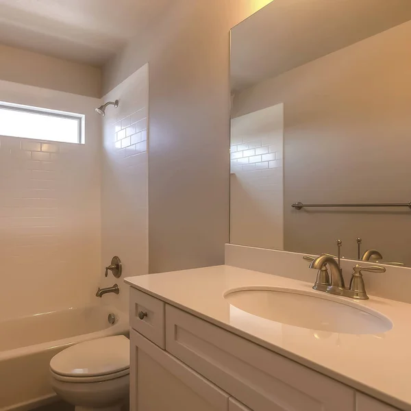 Square Vanity area toilet bathtub and shower inside the bathroom of a home — Stockfoto