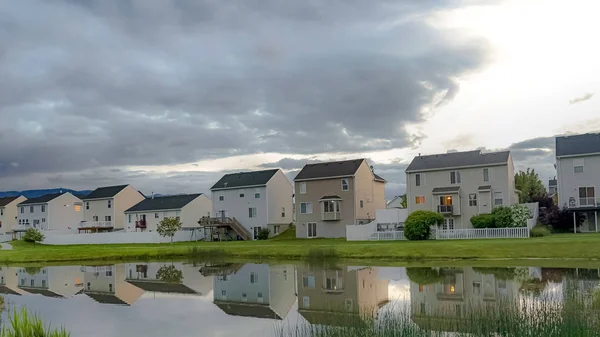 파노라마 프레임 가족 주택과 밝은 흐린 하늘은 빛나는 이웃 연못에 반영 — 스톡 사진