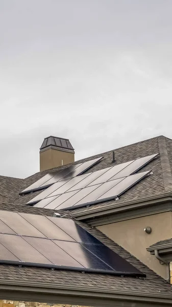 Paneles solares verticales montados en el techo oscuro de una casa bajo el cielo gris nublado — Foto de Stock