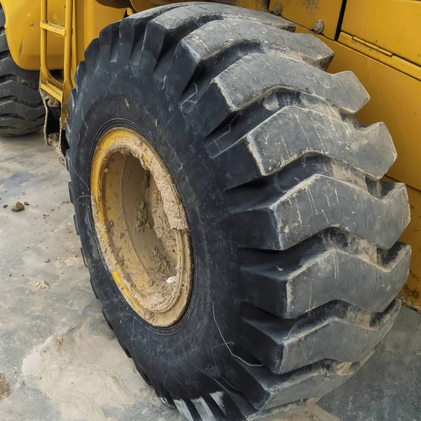 Marco Vista de cerca de la rueda de goma negra de una maquinaria de construcción amarilla —  Fotos de Stock