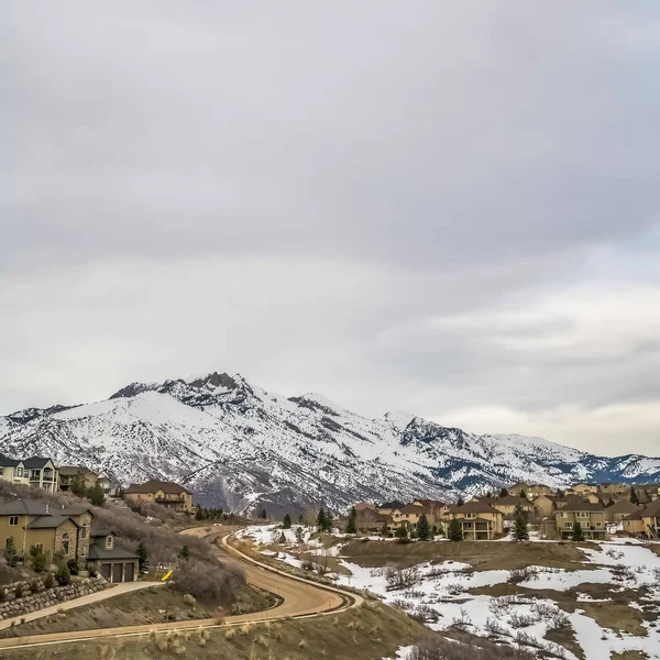 Plaza Curvy carretera y casas construidas en una colina con vista a la alta montaña nevada — Foto de Stock