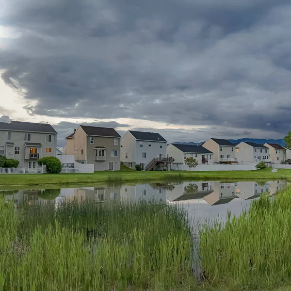Cielo nublado cuadrado sobre un barrio pintoresco con encantadoras casas familiares y estanque brillante — Foto de Stock