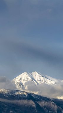 Dikey çerçeve Güneşli beyaz kar ile kaplı zirvesi ile bir dağın güzel görünümü
