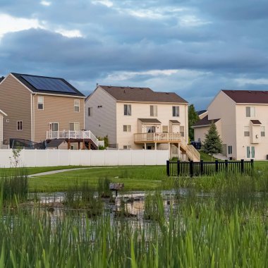 Çok katlı evlerin önünde bir alanın ortasında köprü ile Kare Grassy gölet