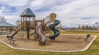 Karla kaplı dağa bakan oyun alanı ve piknik köşkü ile Panorama Park