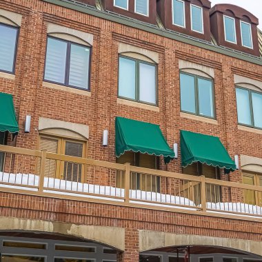 Balkon pencerelerinde yeşil tenteler ile kırmızı tuğla binanın Kare Dış