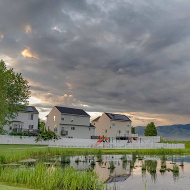 Kare Parlak gölet oyun alanı ve çok katlı evler geniş çimenli arazi ile çevrili