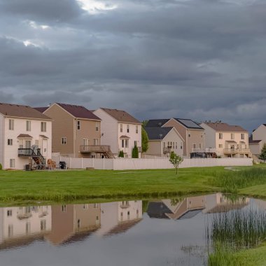 Kare çerçeve Parlak bir gölet ve geniş çimenli alan manzaralı güzel evler