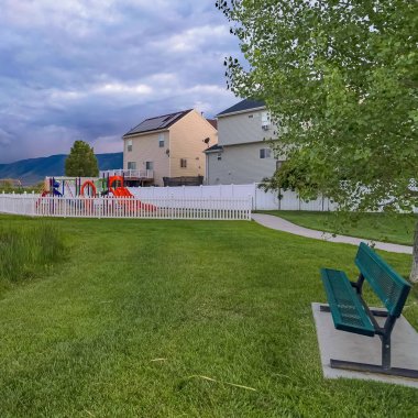 Kare çerçeve Tezgah ve arka planda oyun alanı ve evleri ile çimenli bir parkta gölet