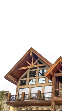 Bulutlu gökyüzüne karşı ahşap aksan balkon ve parlak pencereler ile Dikey Ev cephe