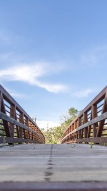 Dikey çerçeve Güneşli bir günde mavi gökyüzüne karşı bir köprünün ahşap güverte ve paslı korkuluklar