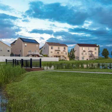 Çok katlı evlerin önünde gölet köprü ağaçları ve tezgah ile Square Grassy park