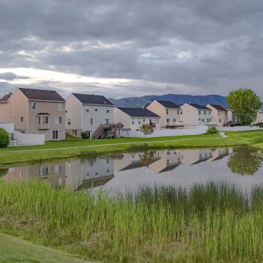 Balkonlu güzel evlerin önünde çimenli bir parkta köprü ile Square Shiny gölet