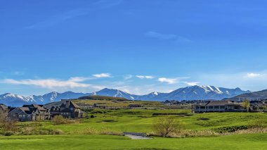Panorama Homes güneşli bir günde uçsuz bucaksız mavi gökyüzü altında otlarla kaplı arazi üzerine inşa