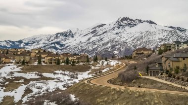 Panorama çerçeve Curvy yol ve evler yükselen kar kaplı dağ manzaralı bir tepe üzerine inşa
