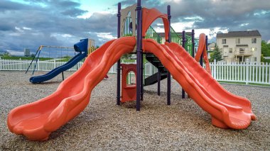 Panorama çerçevesi Bulutlu mavi gökyüzü altında bir mahalle oyun alanı renkli slaytlar ve salıncaklar