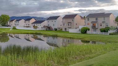 Balkonlu güzel evlerin önünde çimenli bir parkta köprü ile Panorama Shiny gölet